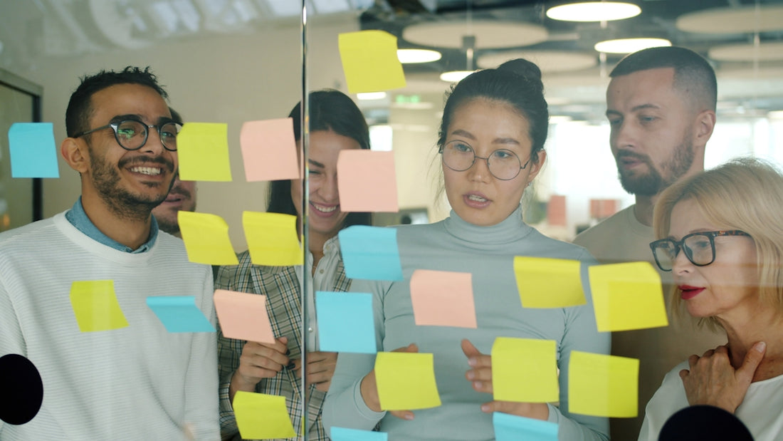 Team brainstorming with colorful sticky notes on glass.